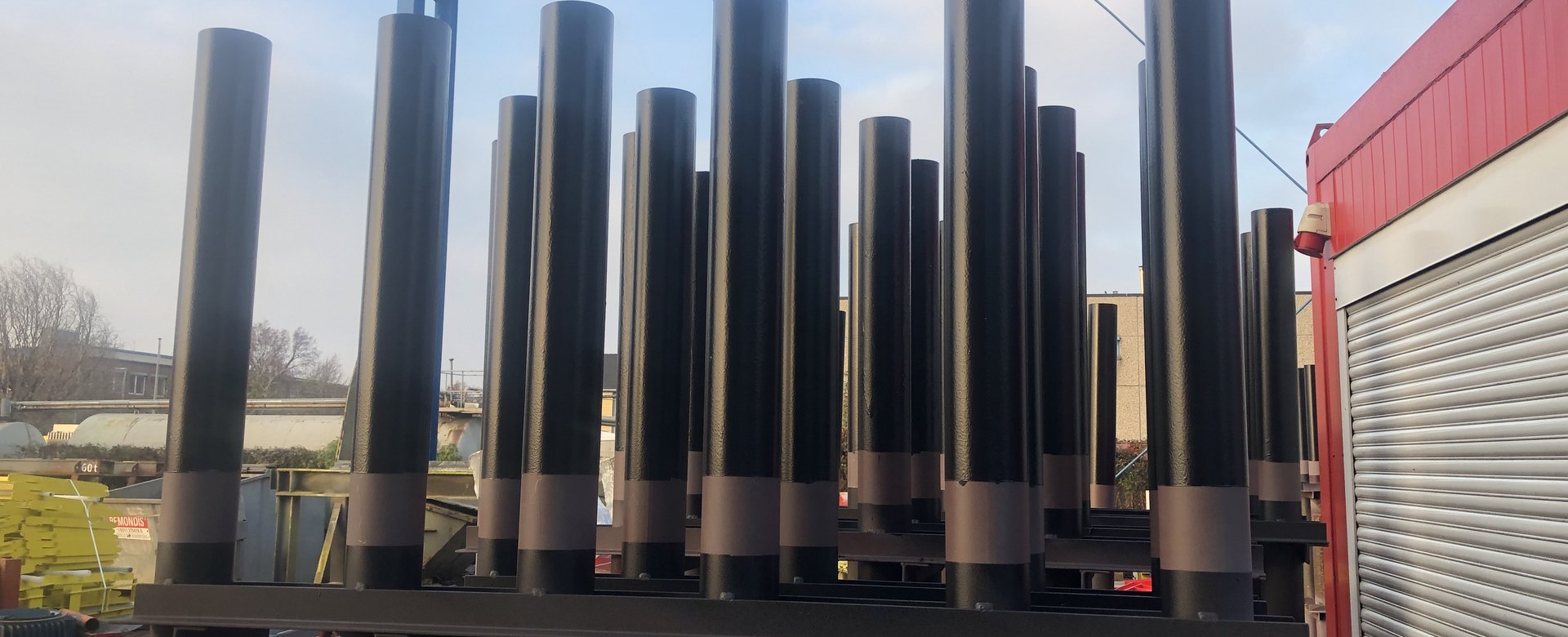 Mehrere schwarze Stahlsäulen im Außenbereich, nebeneinander gelagert