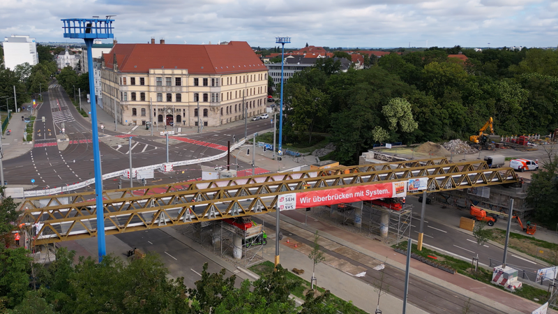 Ansicht der Behelfsbrücke am Damaschkeplatz in Magdeburg mit großem Banner mit der Aufschrift: Wir überbrücken mit System.