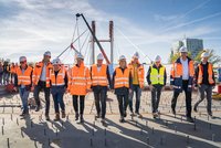 Gruppenbild Projektbeteiligter mit Helm und Warnweste. Gehen über die Brücke.