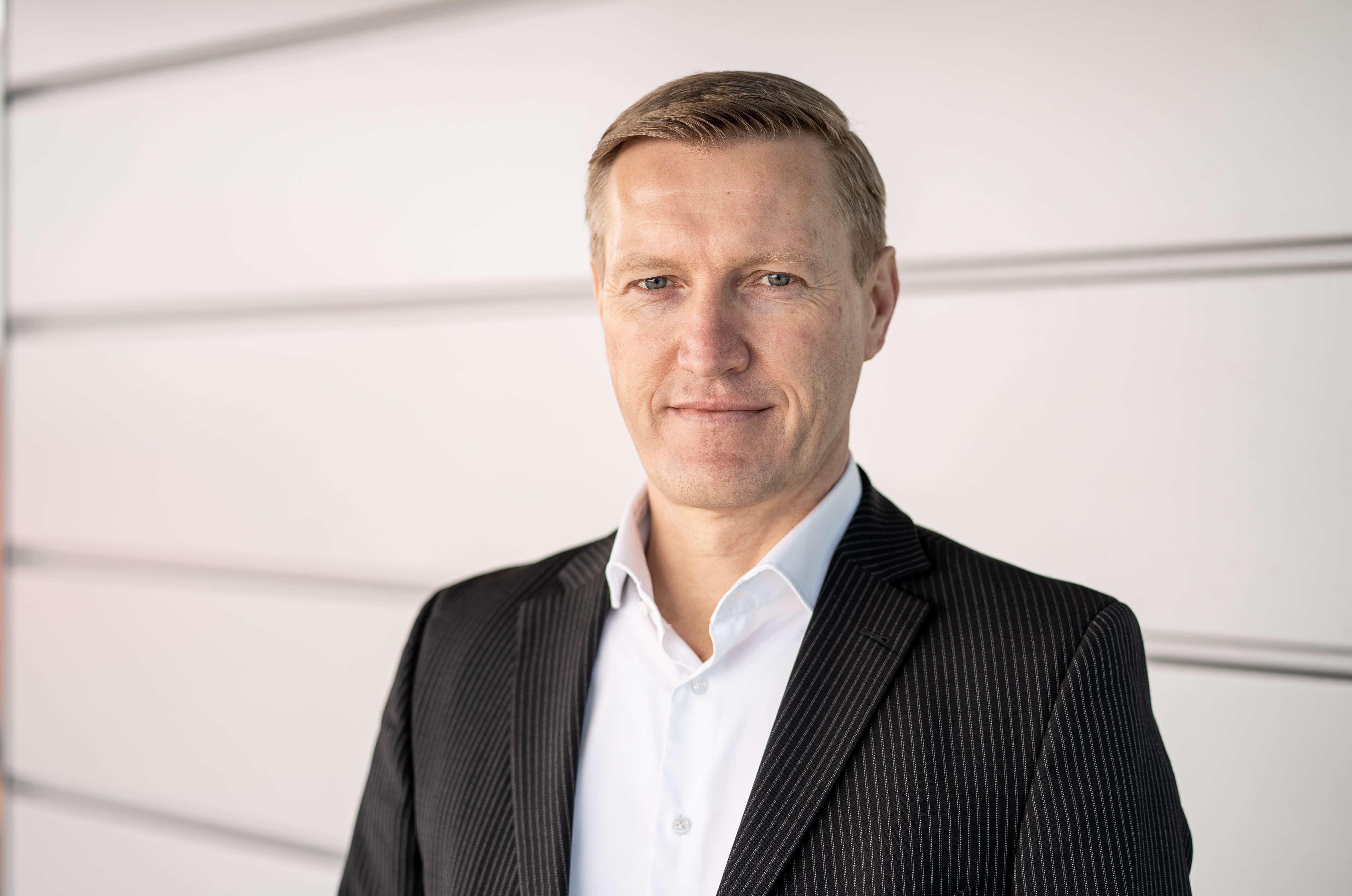 Foto des Geschäftsführers "Meik Schücke" in einem dunklen Anzug, freundlich lächelnd in die Kamera blickend. Er steht vor einem neutralen Hintergrund.