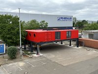 Roter Containerkomplex mit Stützen und Parkplätzen darunter