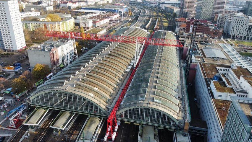 Blick auf die Dächer des Berliner Ostbahnhofs. Daneben eine großer roter Portalkran.