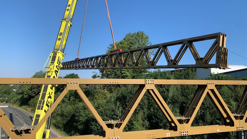 Gelber Kran hebt ein Brückenelement der Behelfsbrücke.