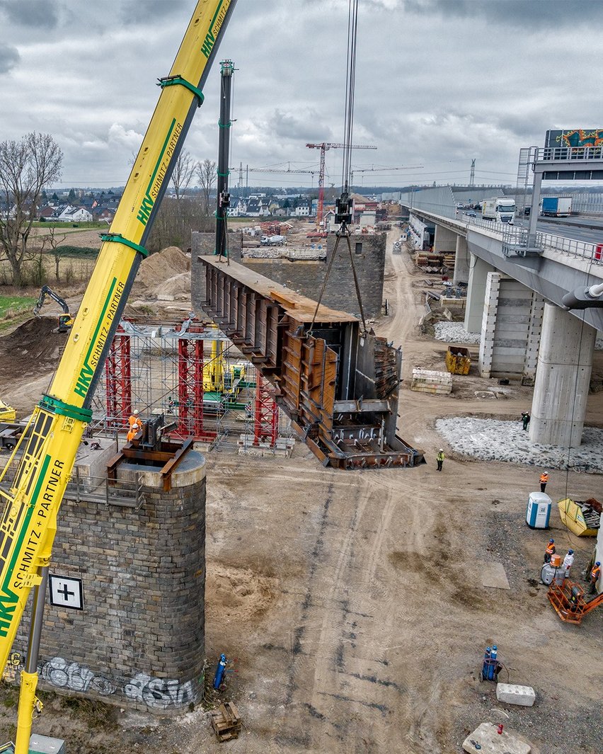 Auf der Baustelle hebt ein Kran ein altes Brückenelement.