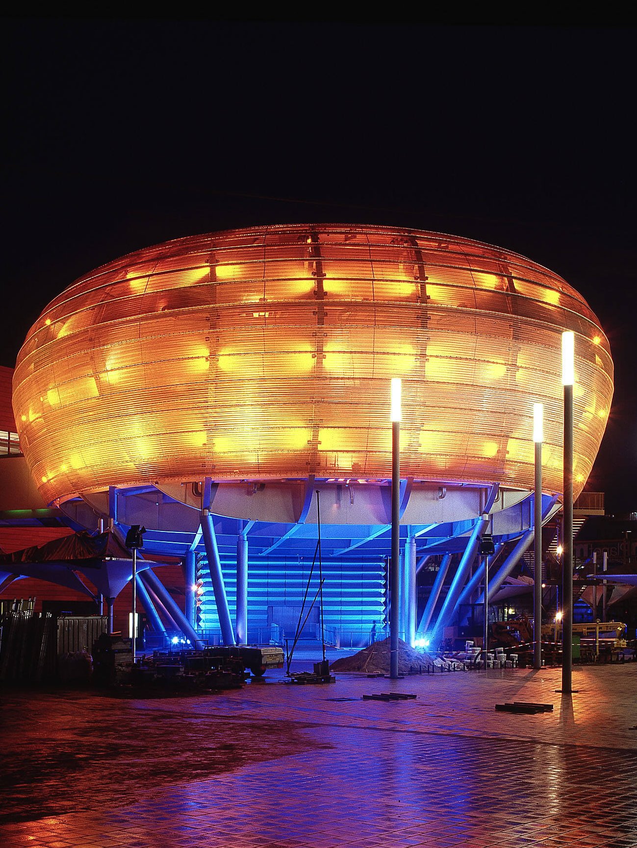Orange und blau beleuchteter Bertelsmann-Pavillon "Planet M" bei Nacht